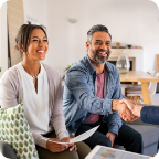 A couple smile and shake hands with an independent insurance agent. 
